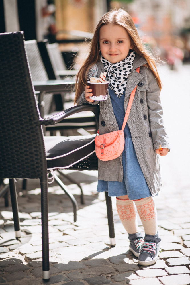 mała dziewczynka w płaszczu i różowa torebką